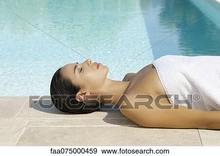 Woman sunbathing by pool View Large Photo Image Stock Photo - Woman sunbathing by pool. Fotosearch