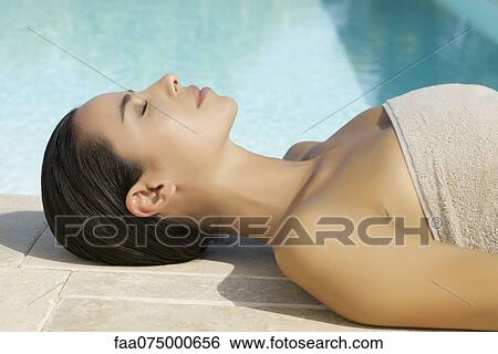 Stock Photograph - Woman sunbathing by pool. Fotosearch