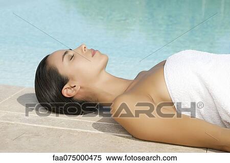Stock Photography - Woman sunbathing by pool. Fotosearch