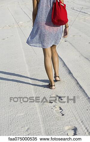 Stock Photography - Woman walking on beach, rear view. Fotosearch