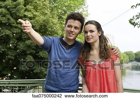 Young couple outdoors, young man pointing into distance, portrait View Large Photo Image Stock Image - Young couple outdoors, young man pointing into distance, portrait. Fotosearch