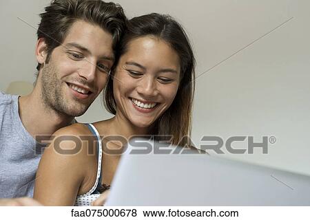 Stock Photo - Young couple using laptop computer together, low angle view. Fotosearch