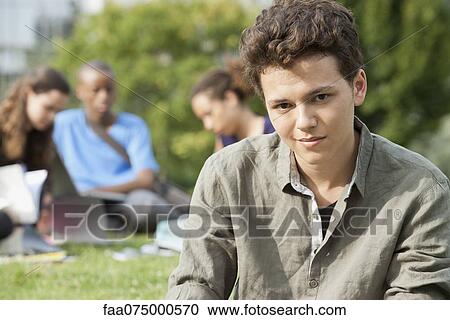 Young man outdoors, people in background, portrait View Large Photo Image Stock Image - Young man outdoors, people in background, portrait. Fotosearch
