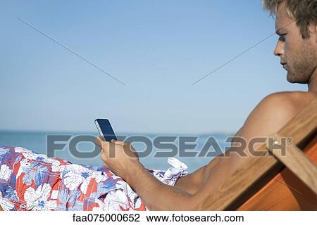 Young man text messaging on beach View Large Photo Image Stock Image - Young man text messaging on beach. Fotosearch
