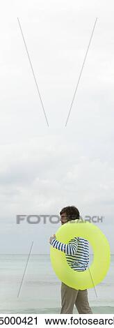 Young man with inflatable ring, looking at ocean View Large Photo Image Stock Image - Young man with inflatable ring, looking at ocean. Fotosearch