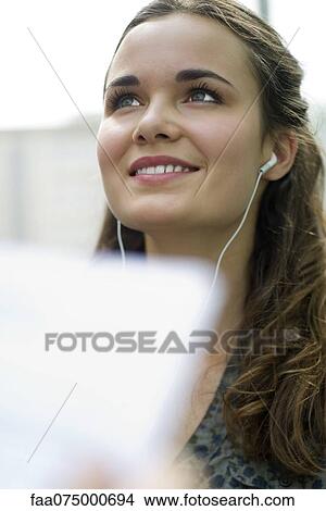 Picture - Young woman listening to music with earphones. Fotosearch