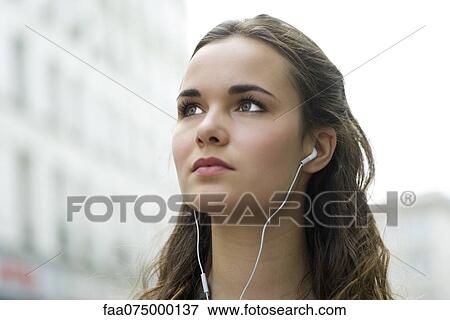 Young woman listening to music with earphones View Large Photo Image Stock Photo - Young woman listening to music with earphones. Fotosearch