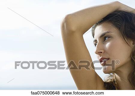 Young woman looking away in thought, hand on head View Large Photo Image Stock Photo - Young woman looking away in thought, hand on head. Fotosearch