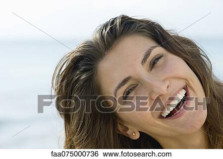 Stock Photograph - Young woman outdoors, smiling cheerfully, portrait. Fotosearch