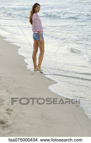 Picture - Young woman standing on beach. Fotosearch