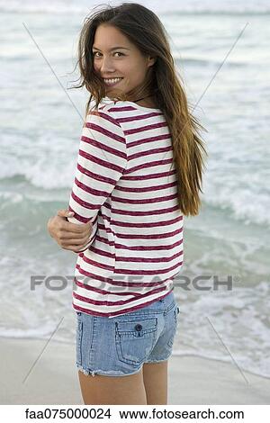Young woman standing on beach, portrait View Large Photo Image Picture - Young woman standing on beach, portrait. Fotosearch