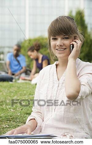Stock Photography - Young woman talking on cell phone outdoors, portrait. Fotosearch