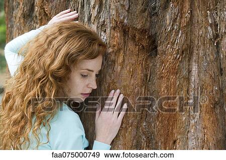 Young woman touching tree, portrait View Large Photo Image Stock Photo - Young woman touching tree, portrait. Fotosearch