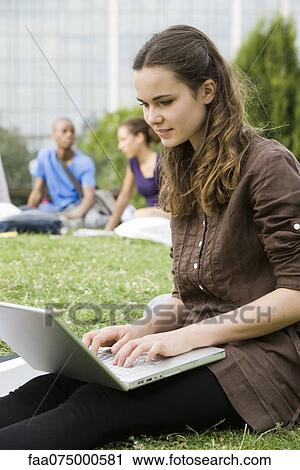Young woman using laptop computer outdoors, people in background, portrait View Large Photo Image Stock Image - Young woman using laptop computer outdoors, people in background, portrait. Fotosearch