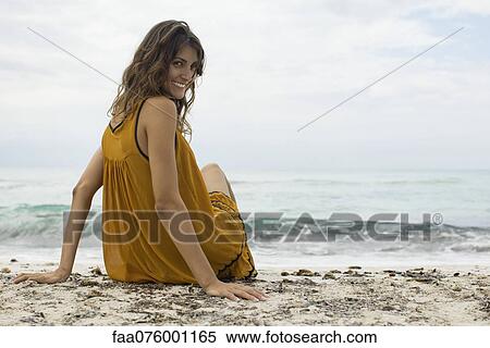 若い女性 ビーチの上に座る 終わる 肩を 見ること カメラにおいて ストックフォト 写真素材 Faa Fotosearch