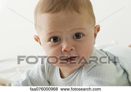 Stock Photo - Baby boy looking at camera with wide eyes, portrait. Fotosearch