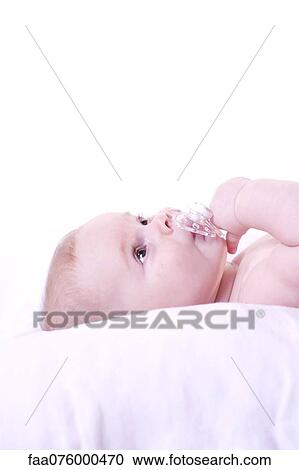 Stock Image - Baby lying down with pacifier in mouth. Fotosearch