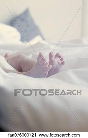 Stock Image - Baby's bare feet on bed. Fotosearch