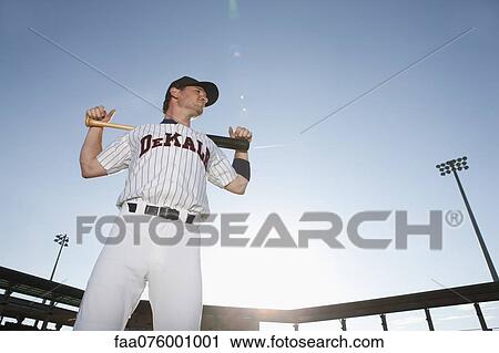 Stock Image - Baseball player holding bat across shoulders. Fotosearch