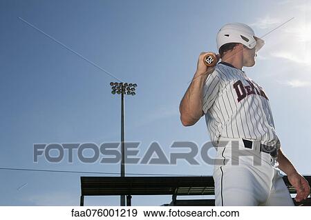Stock Photo - Baseball player holding bat, looking over shoulder. Fotosearch