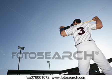 Stock Image - Baseball player holding bat, rear view. Fotosearch