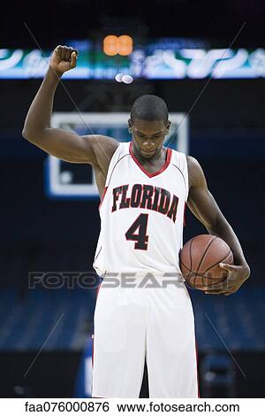 Stock Photograph - Basketball player cheering with arm raised, portrait. Fotosearch