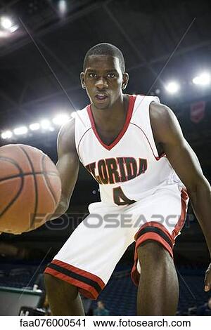 Stock Image - Basketball player dribbling basketball, low angle view. Fotosearch