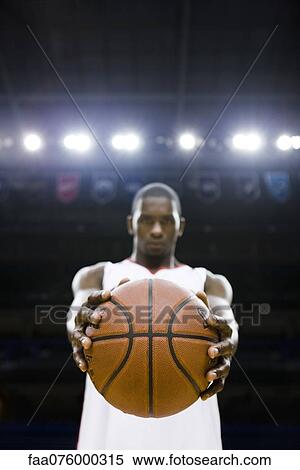 Stock Photography - Basketball player holding basketball, focus on foreground. Fotosearch