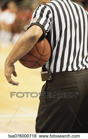 Stock Photo - Basketball referee holding basketball, rear view. Fotosearch