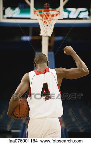 Picture - Basketball with fist raised in victory, rear view. Fotosearch