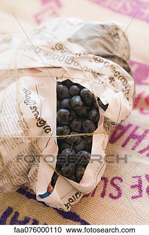 Stock Image - Black grapes wrapped in newspaper. Fotosearch