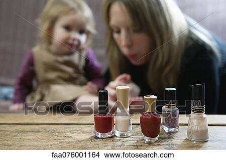Bottles of nail polish, mother blowing on young daughter's toes in background View Large Photo Image Picture - Bottles of nail polish, mother blowing on young daughter's toes in background. Fotosearch
