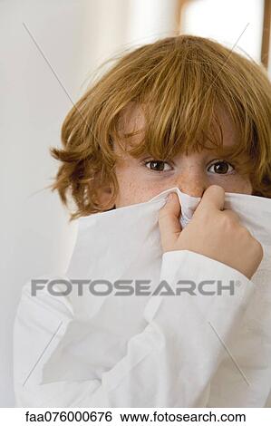 Stock Photograph - Boy blowing nose on tissue. Fotosearch