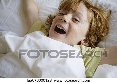 Boy lying in bed View Large Photo Image Stock Photo - Boy lying in bed. Fotosearch
