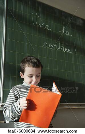Boy reading in front of blackboard in classroom View Large Photo Image Picture - Boy reading in front of blackboard in classroom. Fotosearch