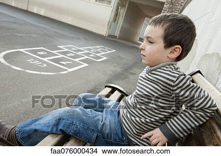Boy sitting on bench, looking sad View Large Photo Image Picture - Boy sitting on bench, looking sad. Fotosearch