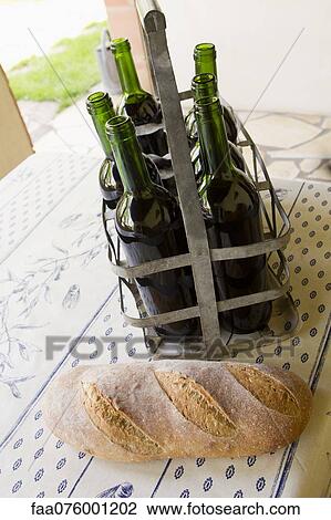 Stock Image - Bread and bottles of wine on table. Fotosearch