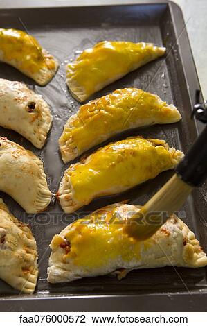 Brushing egg on unbaked empanadas View Large Photo Image Stock Image - Brushing egg on unbaked empanadas. Fotosearch