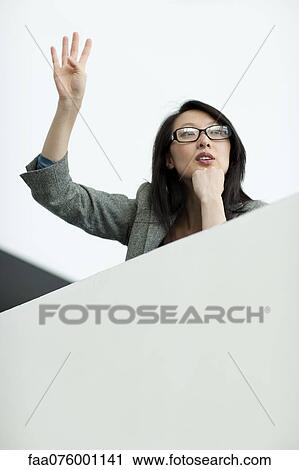 Stock Image - Businesswoman on balcony, waving. Fotosearch