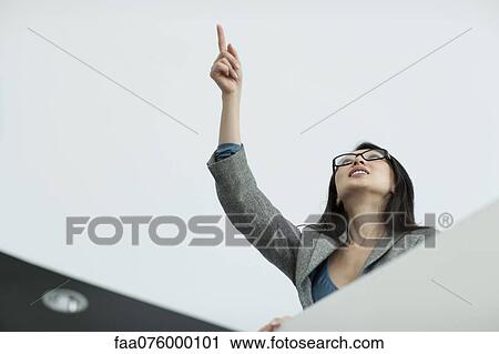 Stock Image - Businesswoman pointing and looking up. Fotosearch