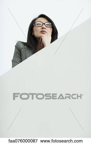 Stock Photo - Businesswoman with hand under chin, looking away, portrait. Fotosearch