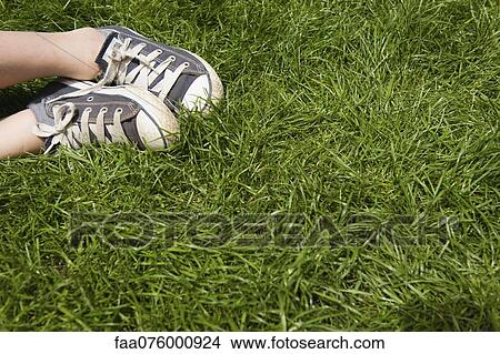 Picture - Child's feet in sneakers on grass, low section. Fotosearch