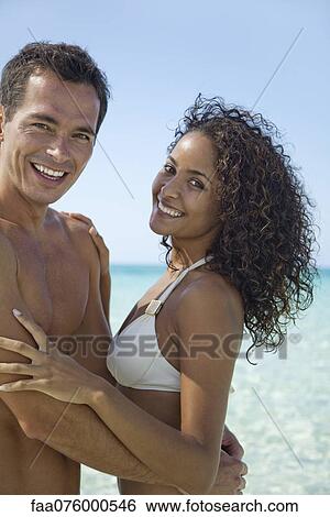 Stock Photograph - Couple embracing at the beach, portrait. Fotosearch