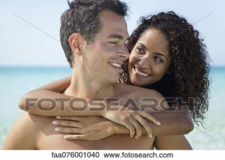 Stock Image - Couple embracing at the beach. Fotosearch