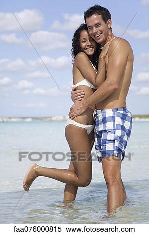 Stock Photography - Couple embracing in water at the beach. Fotosearch