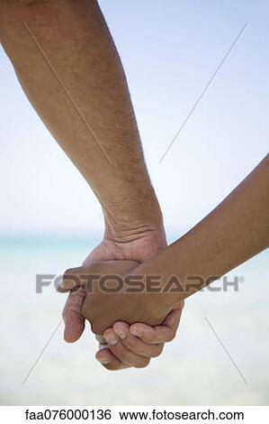 Stock Photograph - Couple holding hands, cropped. Fotosearch
