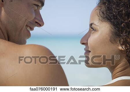 Couple smiling at each other at the beach View Large Photo Image Stock Image - Couple smiling at each other at the beach. Fotosearch