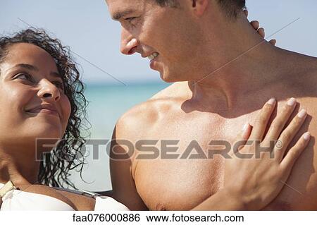 Couple smiling at each other at the beach View Large Photo Image Stock Photograph - Couple smiling at each other at the beach. Fotosearch