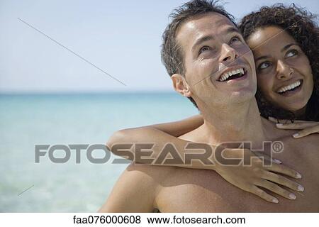 Couple together at the beach, looking up and smiling View Large Photo Image Stock Photo - Couple together at the beach, looking up and smiling. Fotosearch