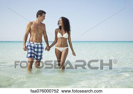 Couple wading hand in hand at the beach View Large Photo Image Stock Image - Couple wading hand in hand at the beach. Fotosearch